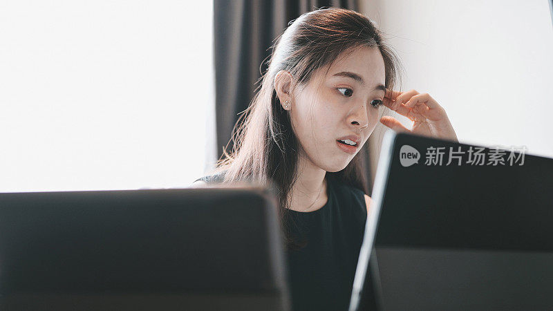 感觉疲惫和压力。亚洲金融商人女性工作在办公室与笔记本电脑担心的工作问题，利润损失的风险，从她的工作