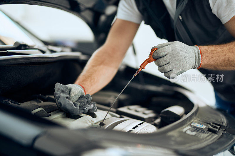 图为汽车修理工在车间检修发动机时检查油位。