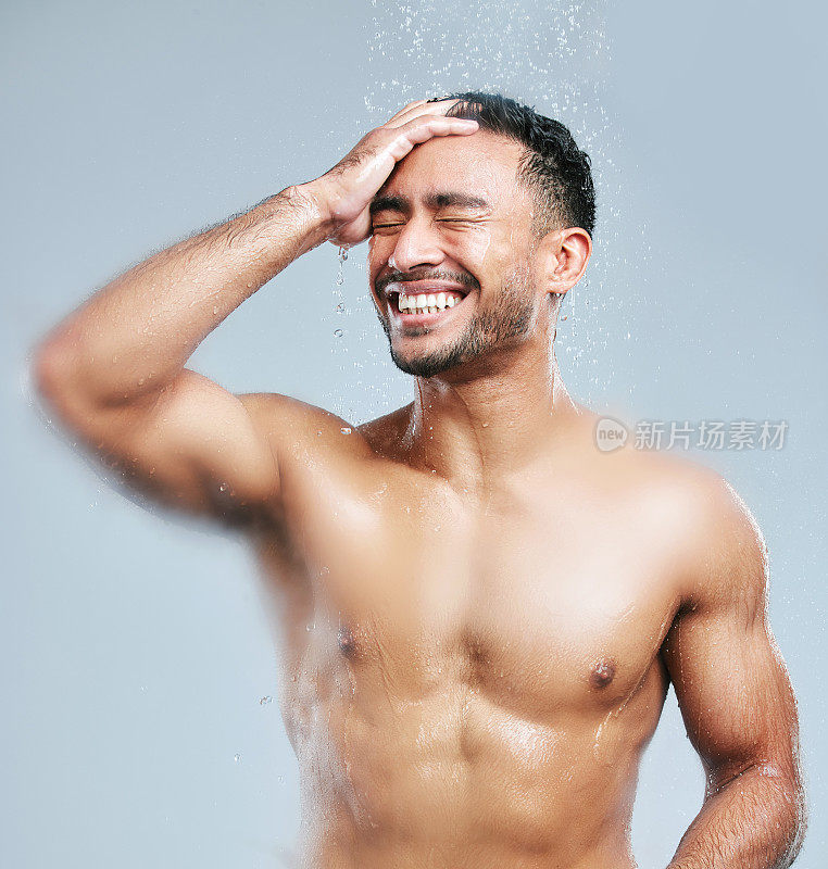 摄影室拍摄的一个英俊的年轻男子淋浴在灰色的背景
