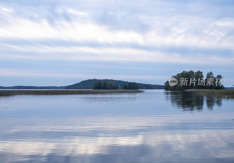 湖上的傍晚景色和日落。湖岸线和天空与美丽的云。