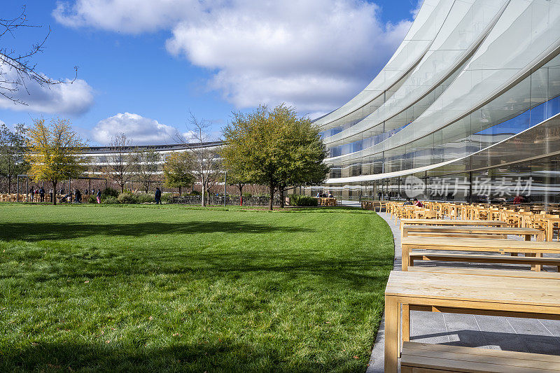 在12月一个晴朗寒冷的日子里，苹果总部办公楼的内外庭院设有户外用餐区。