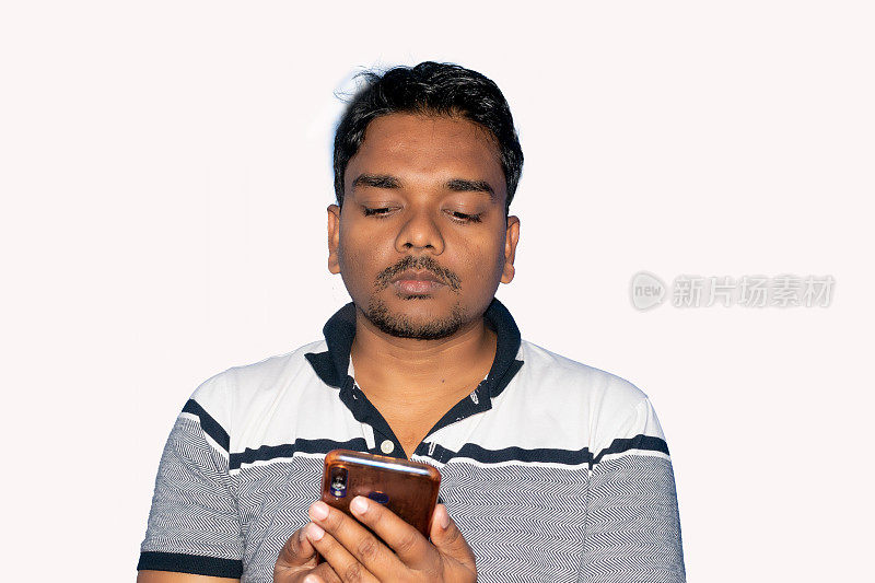 印度一名年轻男子在白色背景下使用手机。选择性地关注脸部。