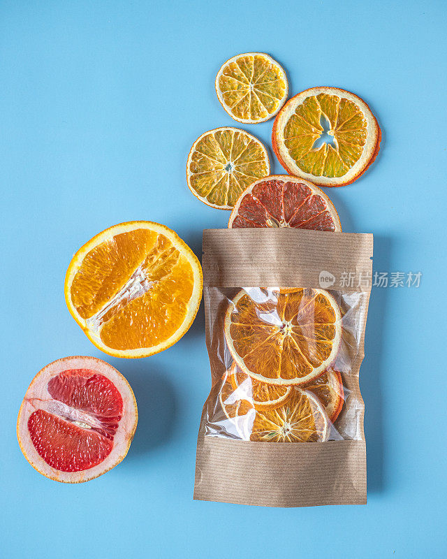 在蓝色的底色上放上成熟的柚子和橙子，配上一个装着柚子、柠檬、橘子、橙子等干柑橘类水果的工艺包