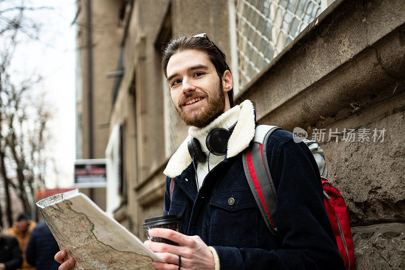 剪裁的镜头，一个英俊的年轻男子看着地图，而游览一个外国城市