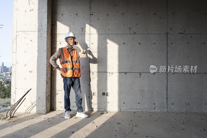 一名男工程师在办公楼建筑工地打电话