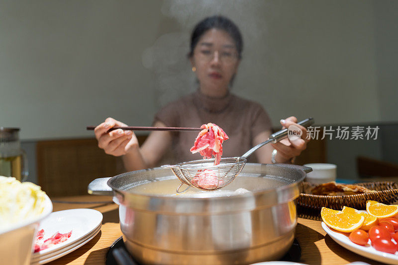 亚洲妇女用筷子夹牛肉