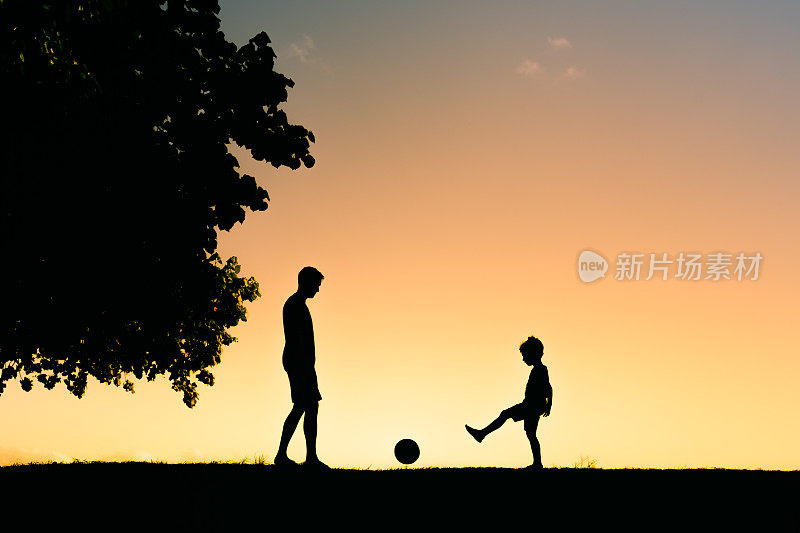 日落时分，父子俩在户外踢足球。