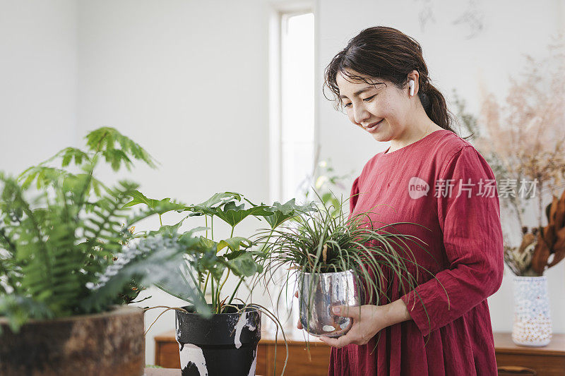 女人在家用无线耳机听音乐和园艺