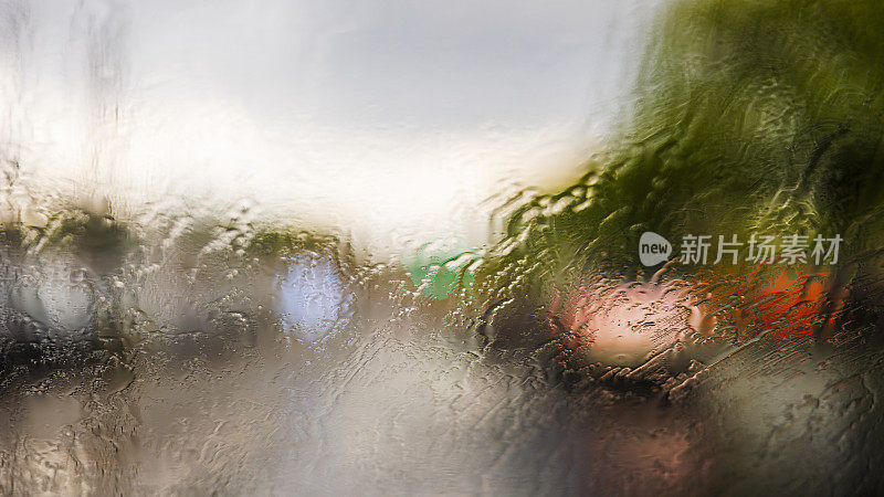 在倾盆大雨中行驶在纽约皇后大道上。从驾驶室看到的挡风玻璃上的风景。街道因为水的影响而变得模糊和扭曲。