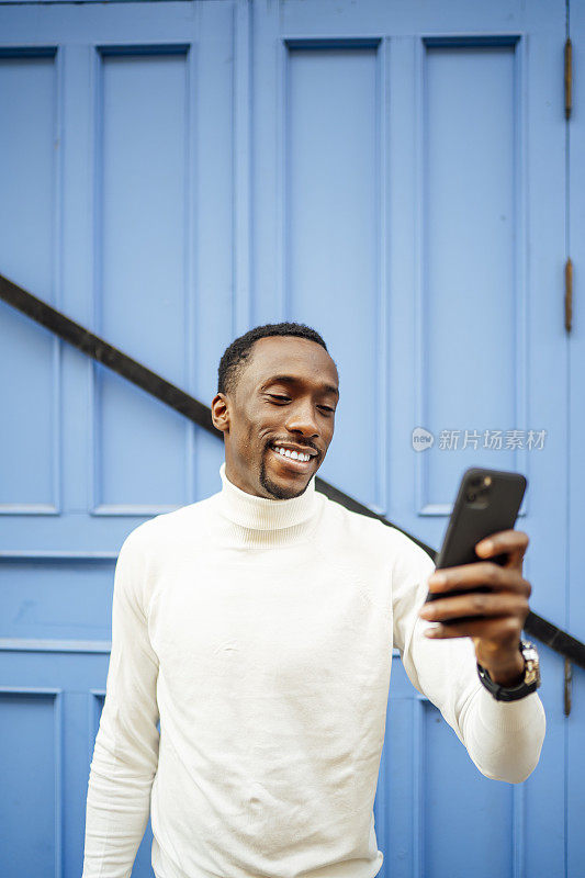 一个穿高领毛衣的黑人男子正在看他的手机