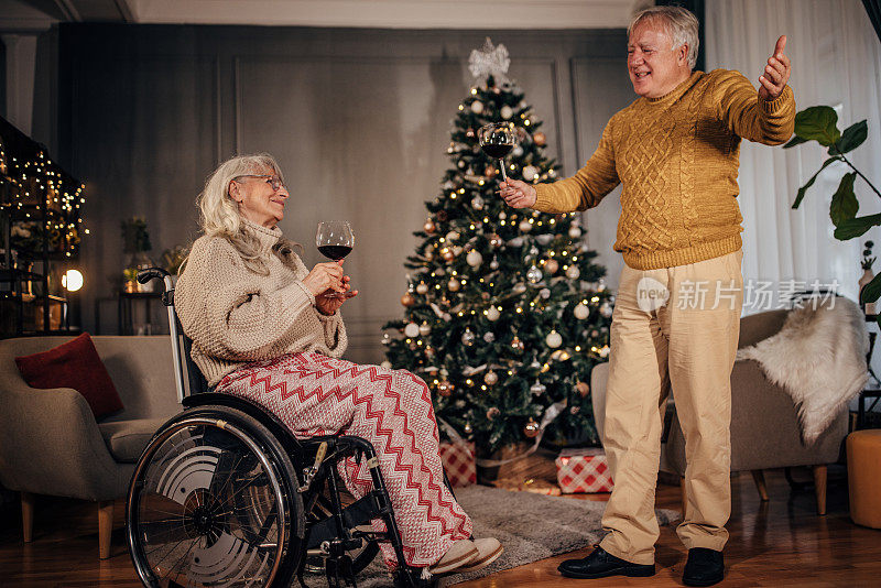 老夫妇在家里的圣诞树旁喝酒