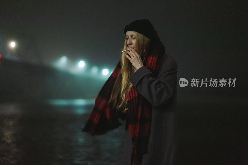 金发女子在夜街抽烟。孤独的