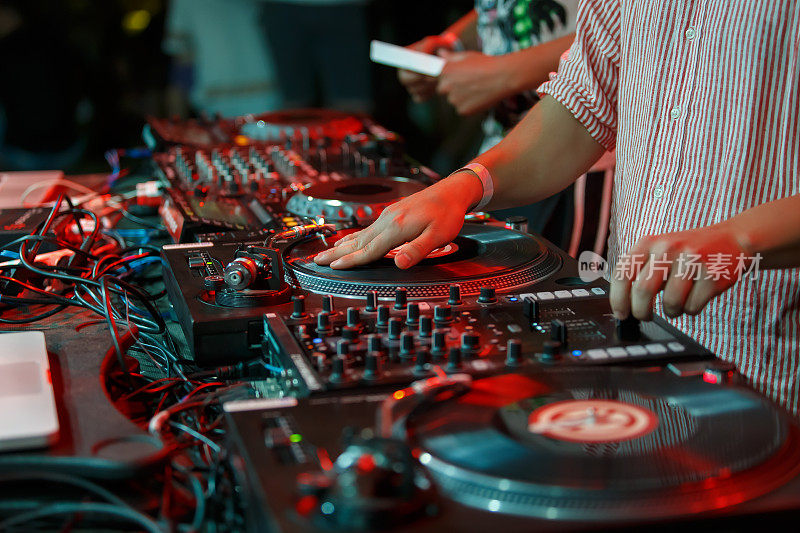 嘻哈dj在夜总会派对上刮黑胶唱片。专业音乐节目主持人的手在转盘上抓挠唱片