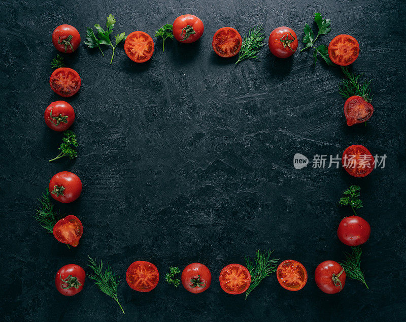 红色的西红柿和绿色的新鲜欧芹和莳萝，以框架的形式躺在深色的背景上。素食的概念。中间的空余空间