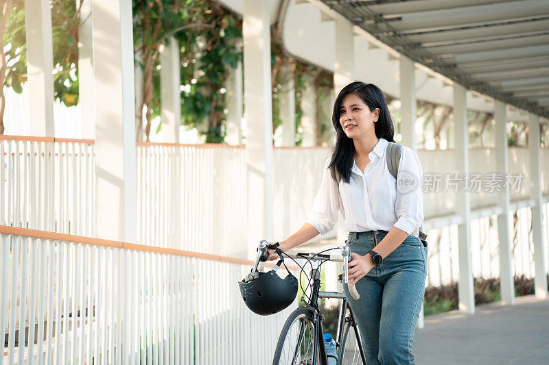 亚洲女性在城市中随意骑自行车上班，在城市中自行车通勤的环保生活方式