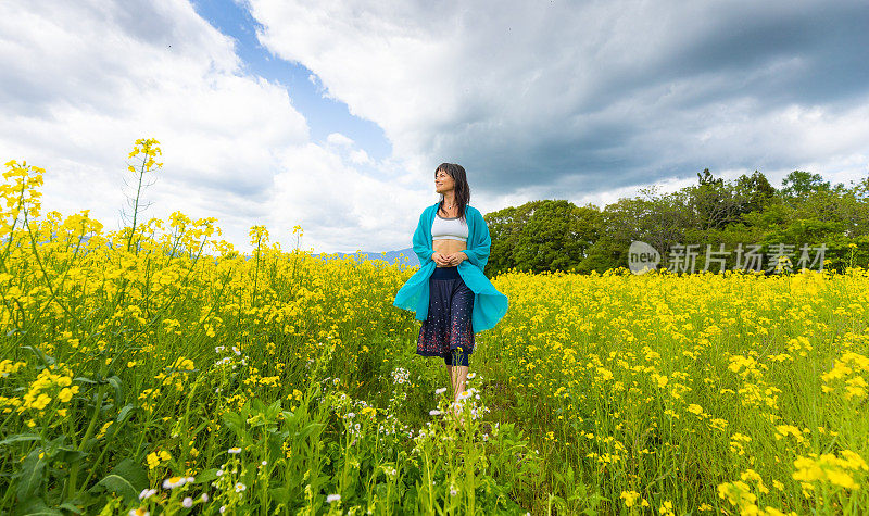 一位妇女在一片黄色的油菜花地里放松和享受户外活动