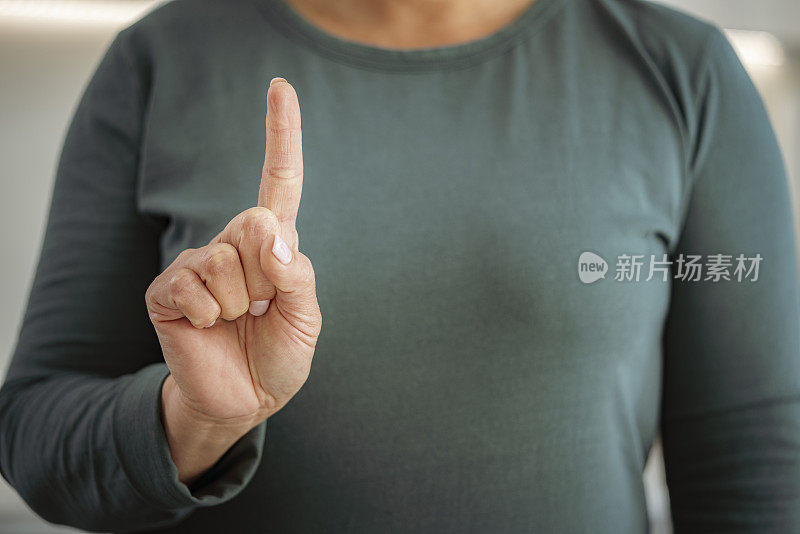 一个无法辨认的女人举起食指的特写