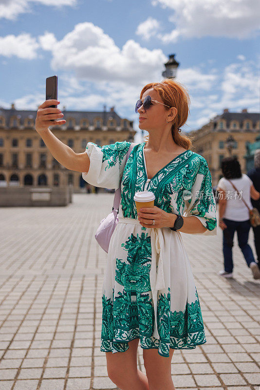 美女在巴黎城市广场用智能手机自拍