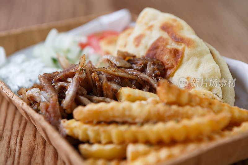 传统的希腊羊肉串肉和皮塔饼，配上白酸奶酱和薯条，装在可回收的纸盘里带走