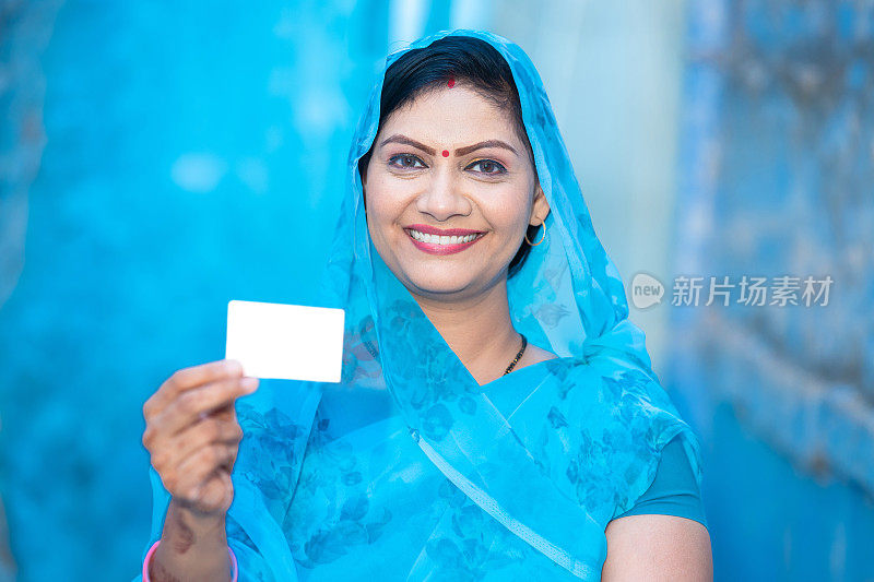 传统的印度妇女展示空白的信用卡借记卡模型，快乐的女性穿着纱丽，拿着空的商务卡或电子卡付款。