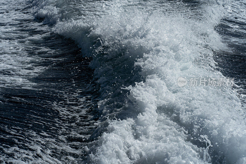 一艘船的痕迹在大海或大洋的背景下，蓝色的海浪和飞溅。海水泡沫表面上的深痕。