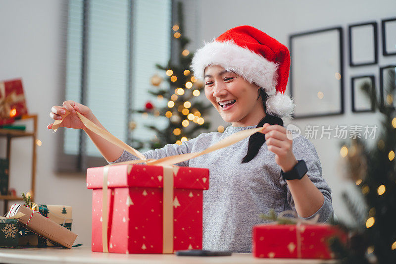 亚洲女人在圣诞节打开礼品盒时玩得很开心。