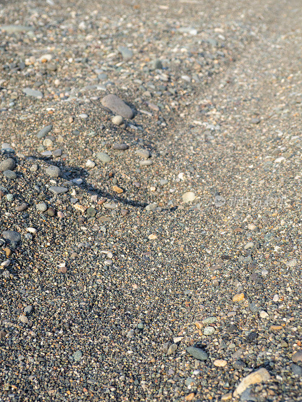 在沙地上车辙。沙滩上的车轮留下的痕迹。沙子和石头。