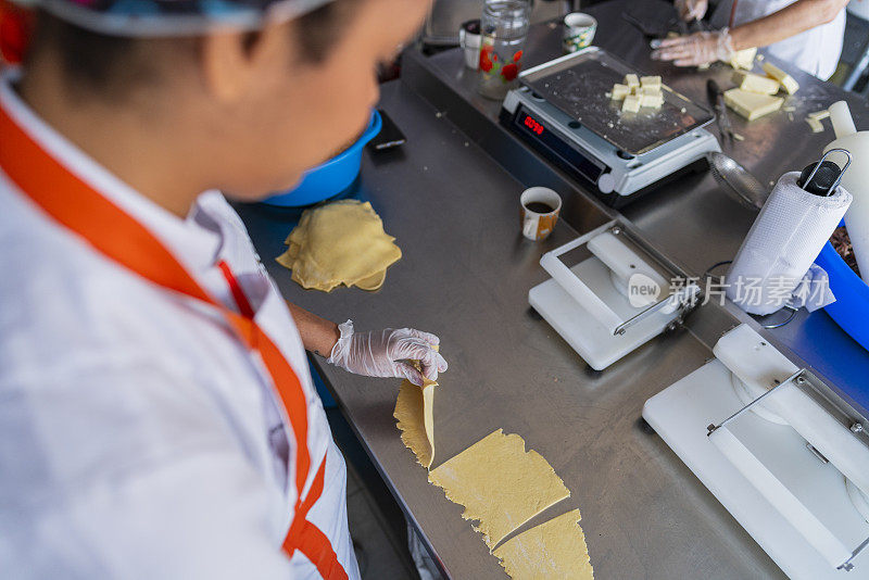 一位拉丁妇女在一家小型肉馅卷饼食品店的厨房里