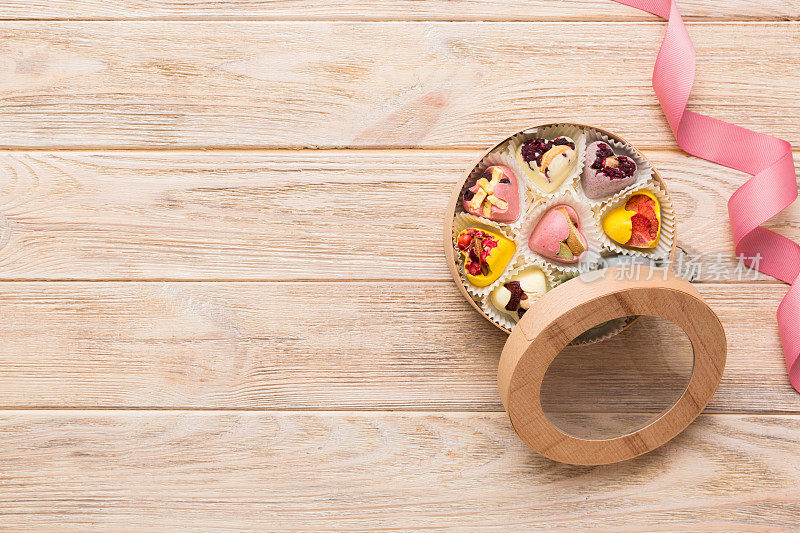 节日构图:甜甜的糖果，带蝴蝶结和巧克力心的礼盒，照片模板，背景。在彩色背景上带有复制空间的俯视图