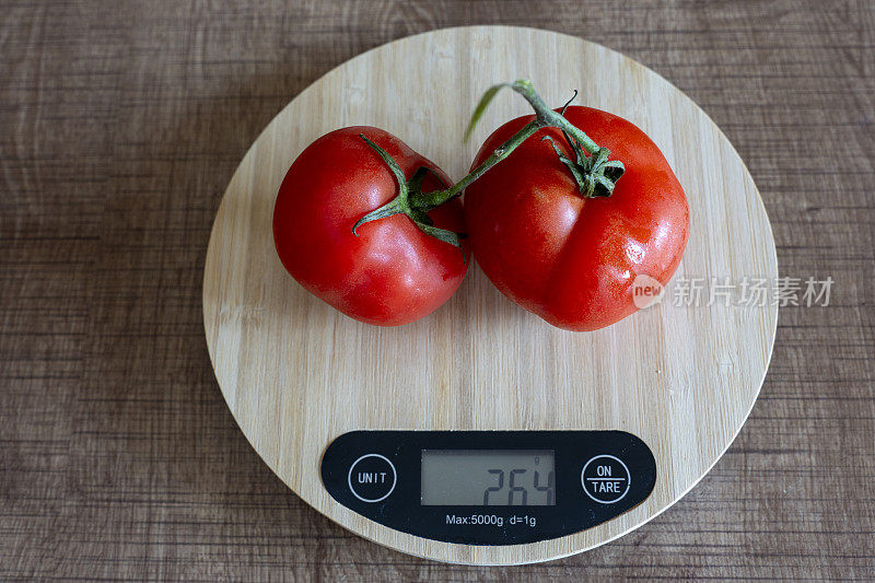 用厨房秤称西红柿的重量。