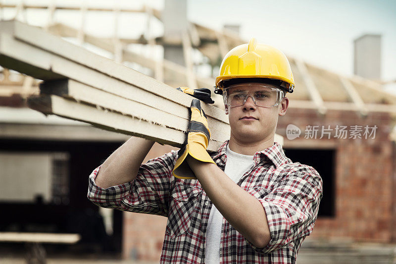 年轻的建筑工人搬运木板