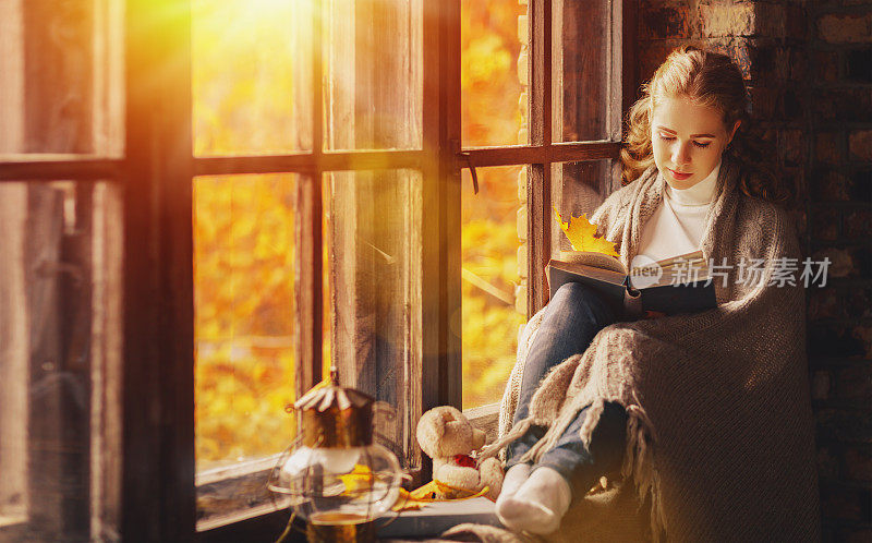 秋天，快乐的年轻女子在窗边看书