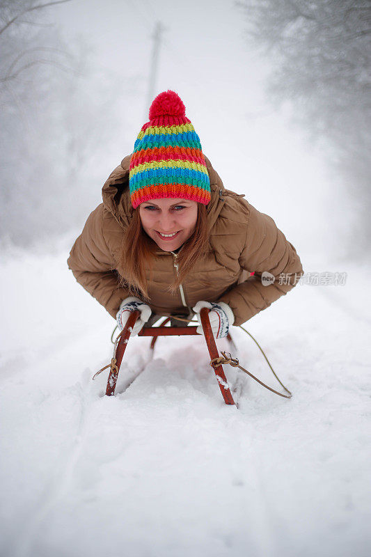 快乐的年轻女子在一个快速的雪橇骑下冰冷的斜坡