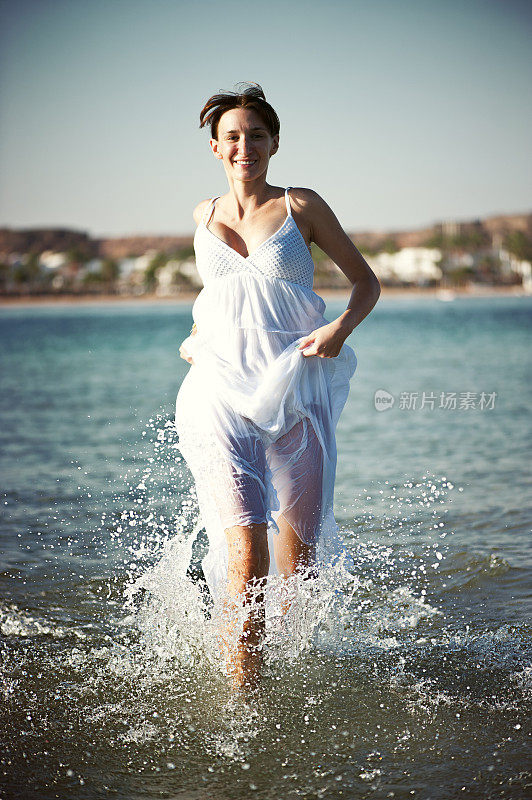 年轻快乐的女人在浅水中奔跑