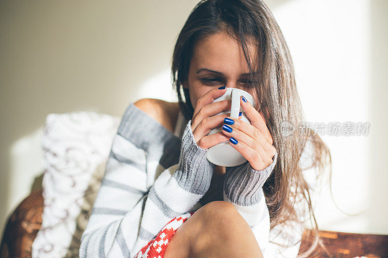 年轻漂亮的女人喝着热咖啡