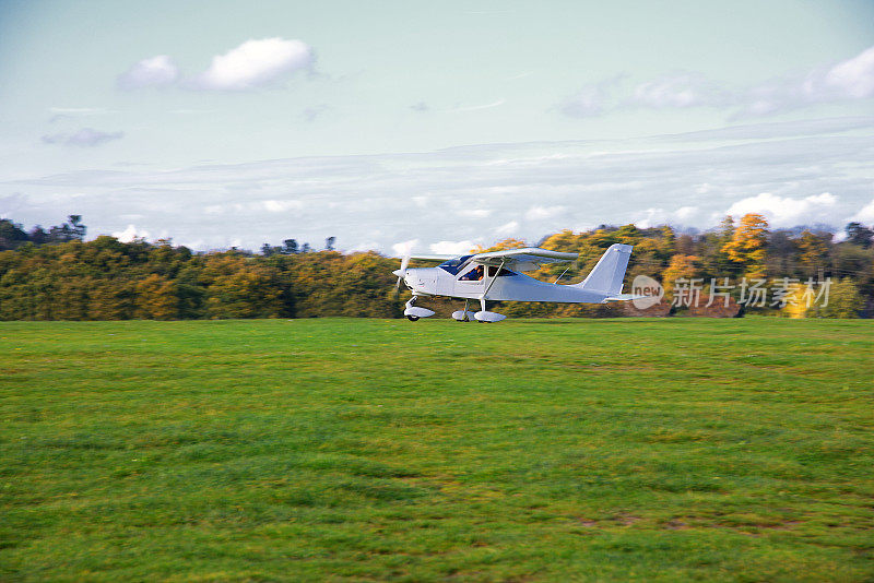 白色运动飞机降落在草地跑道上