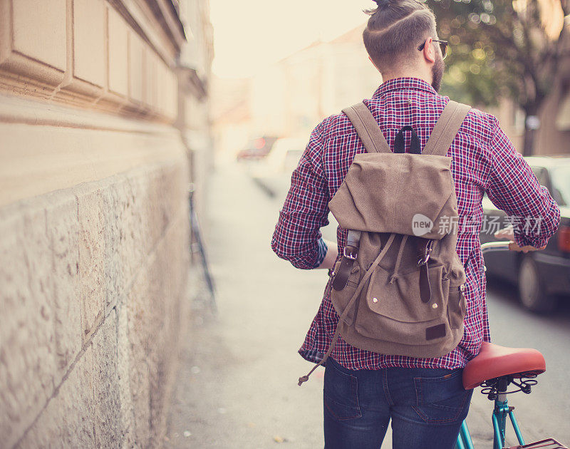 年轻的潮人推着老式自行车在城市街道上