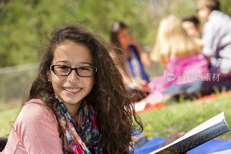 教育:十几岁前的拉丁女孩在当地公园学习。朋友的背景。