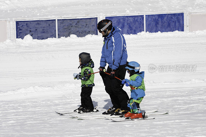 滑雪教练带着两个小男孩