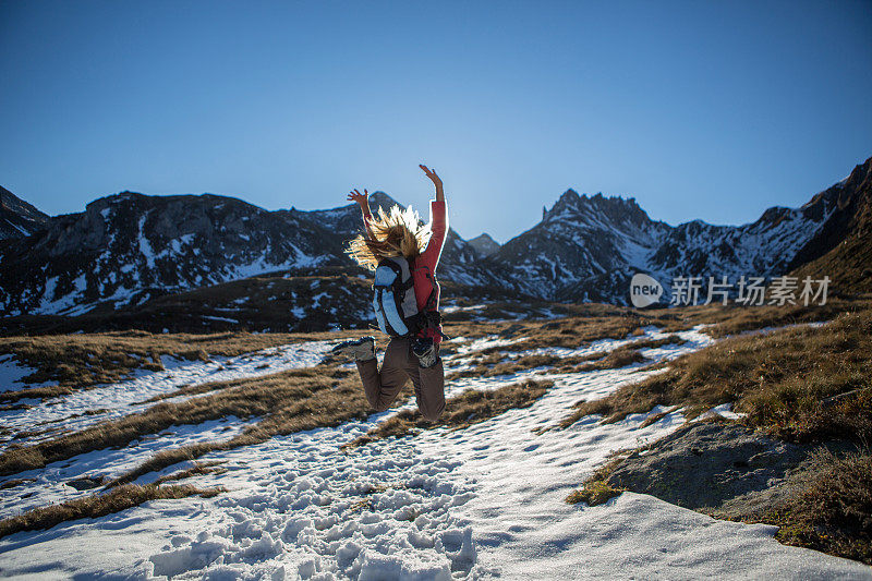 快乐的女人在高山里跳跃在雪地里追求成功