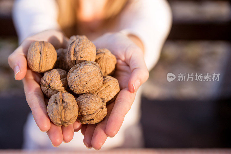 女人拿着一把核桃的照片