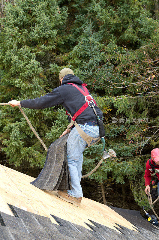 在房屋建造过程中，屋顶工人抓住安全绳索