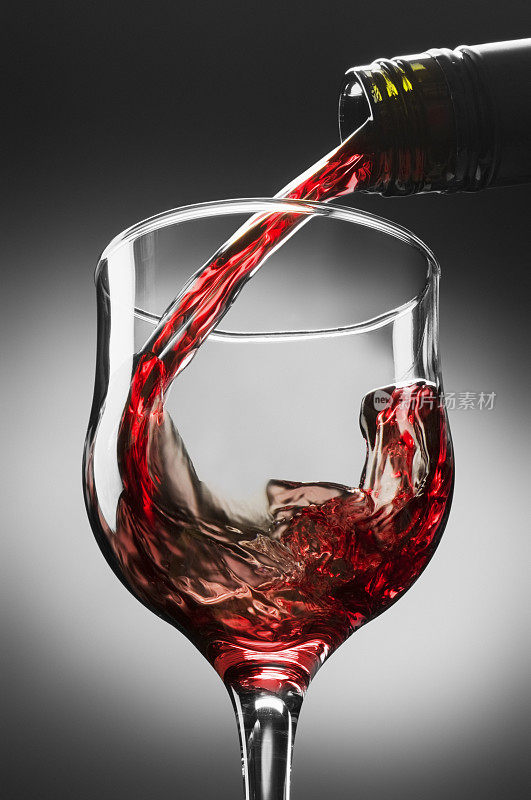 红酒从酒瓶倒入透明的玻璃杯中