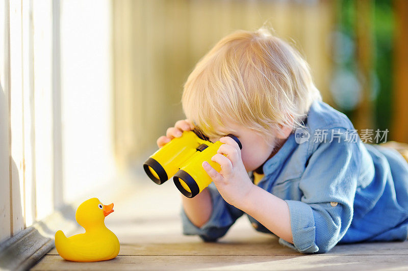 可爱的小男孩在户外玩橡皮鸭和塑料望远镜