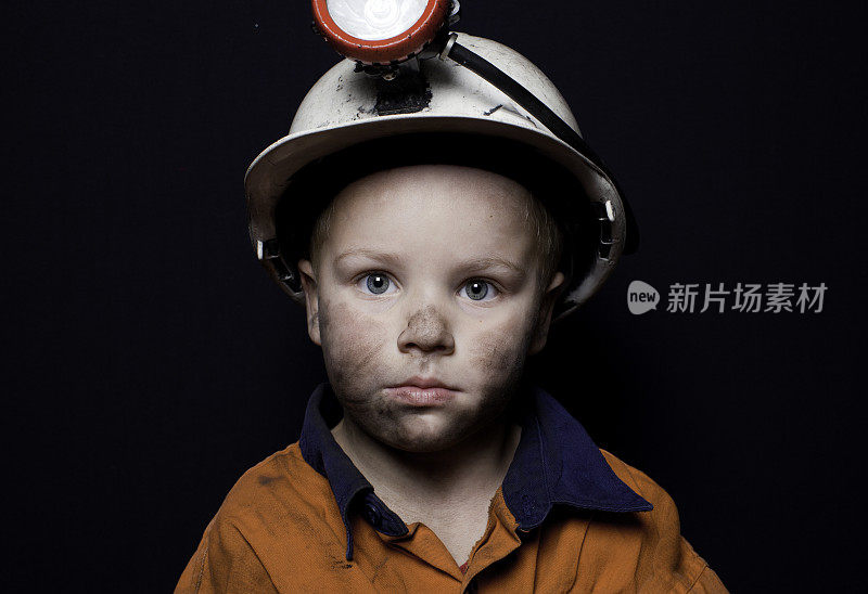 在黑色背景下，穿着煤矿装备的小男孩
