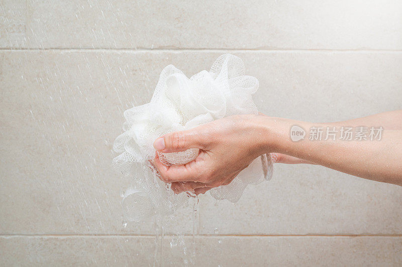 女人在浴室里手持淋浴海绵，洗澡