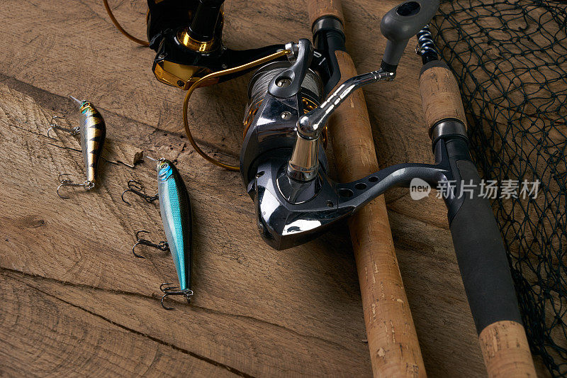 钓鱼设备-钓鱼纺纱，钩，鱼饵和渔网在深色木制背景。前视图。