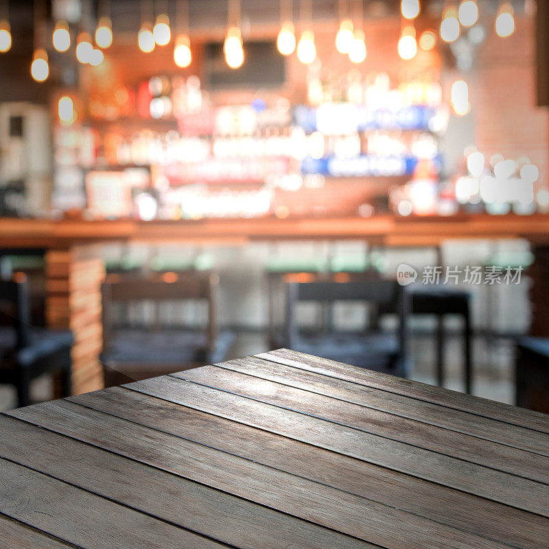在模糊的咖啡馆背景中，空的木质桌面与展示产品的空间。