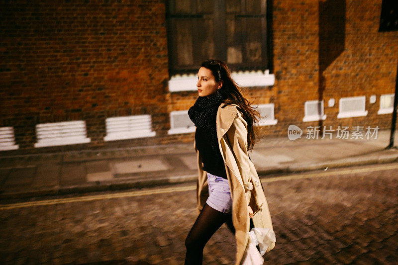 一个年轻的女人在晚上独自走在伦敦市中心的街道上