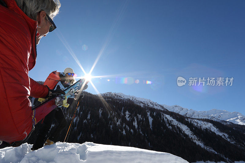 一对夫妇留下滑雪板，在厚厚的积雪中爬上山顶。
